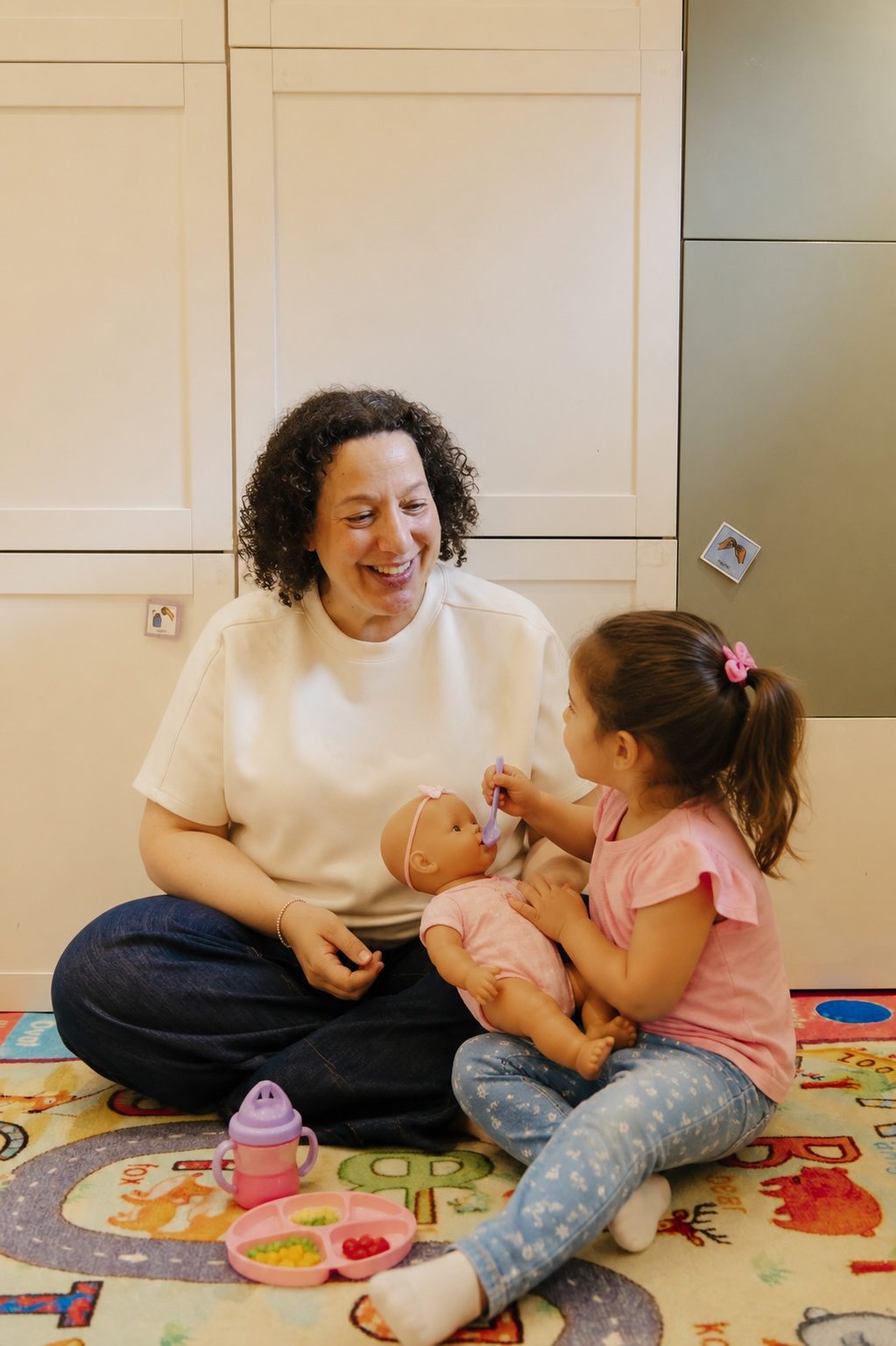 Cynthia in a floor-based play session with a child holding a doll